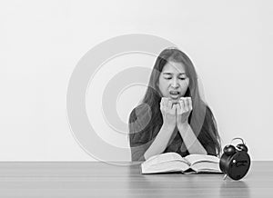 Closeup asian woman sitting for read a book with scary face and shock emotion on wood table and white cement wall textured backgro