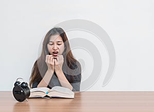 Closeup asian woman sitting for read a book with scary face and shock emotion on wood table and white cement wall textured backgro