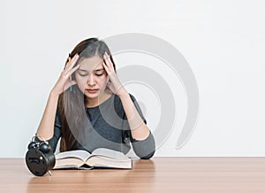 Closeup asian woman sitting for read a book with strain face emotion on wood table and white cement wall textured background in wo
