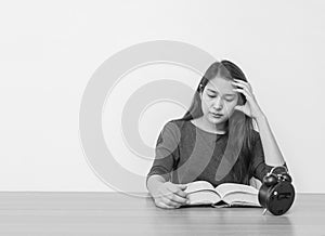 Closeup asian woman sitting for read a book with strain face emotion on wood table and white cement wall textured background in wo