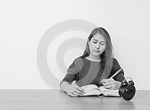 Closeup asian woman sitting for read a book in work concept on wood table and white cement wall textured background in black and w