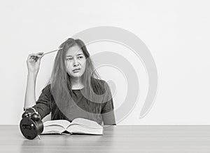 Closeup asian woman tired from reading a book with boring face emotion in work concept on wood table and white cement wall texture