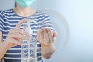 Closeup Asian woman wearing protective mask using hand sanitizer by pumping alcohol gel. Cleaning her hands with sanitizer gel. in
