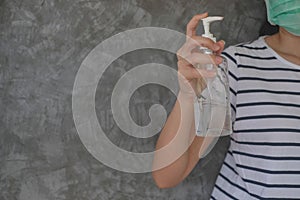 Closeup Asian woman wearing protective mask using hand sanitizer by pumping alcohol gel. Working from home. Cleaning her hands