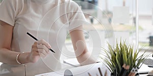 Closeup asian woman writing on notebook on table with laptop, girl work at coffee shop, freelance business concept.