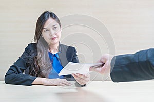 Closeup asian working woman receive work document from her boss with unwilling face in meeting room on blurred wooden desk and