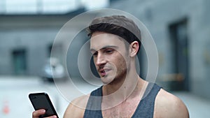 Closeup athlete man looking smartphone on street. Smiling man reading message