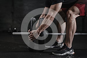 Closeup of athlete preparing for lifting weight at crossfit gym. Barbell magnesia protection. Practicing functional training p