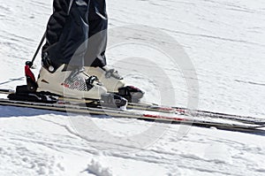 Closeup of an athlete`s foot in ski boots and skiing on a mountainside on a sunny day. Winter sports concept