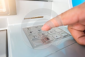 Closeup ATM machine and finger hand entering pressing password for withdrawing money banknotes