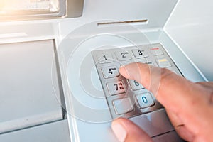 Closeup ATM machine and finger hand entering pressing password for withdrawing money banknotes