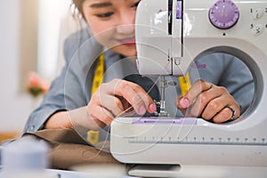 Closeup of attractive female fashion designer hand working workshop with sewing machine. Stylish fashionista woman creating new