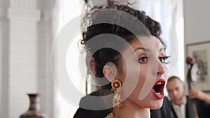 Closeup of attractive girl with red lips in beautiful earrings emotionally sings