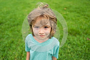 Closeup attractive laughing boy. Child emotions concept. Portrait of young smiling kid outdoor. Grass background.