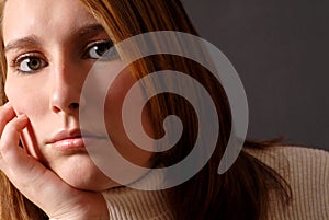 Closeup of an attractive young woman with her chin resting on he