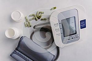 Closeup of an automatic blood pressure meter and pills.