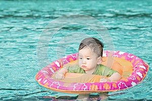 Closeup a baby boy sit in a boat for children in the swimming pool background