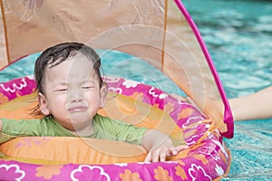 Closeup a baby boy sit in a boat for children in the swimming pool background in fear emotion