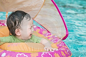 Closeup a baby boy sit in a boat for children in the swimming pool background in fear emotion