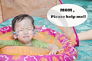 Closeup a baby boy sit in a boat for children in the swimming pool background in fear emotion and need help by his mom