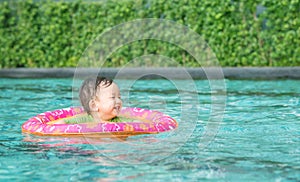 Closeup a baby boy sit in a boat for children in the swimming pool background with smile face in happy emotion