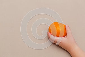 Closeup of baby hands holding tangerine with leaf, healthy eating concept