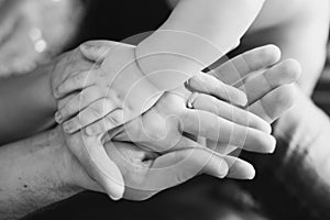 Closeup of baby's and parent's hands. black and white picture