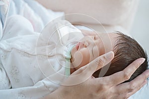 Closeup a baby sleeping comfortably in in the mother`s arms