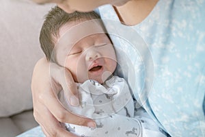 Closeup a baby sleeping comfortably in the mother`s arms