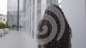 Closeup back view from behind lady businesswoman female girl with curly long hair brunette woman walking going moving in