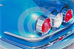 Closeup of backlights of a retro shiny blue car under the sunlight