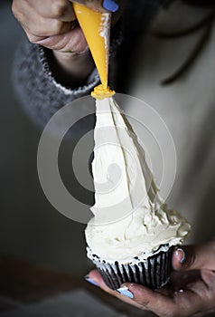 Closeup of baker decorating a cupcake