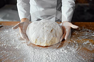 Closeup baker hands holding kneaded dough to prepare fresh bread