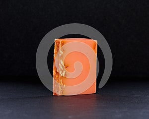 Closeup of a bar of orange-scented soap against a black background