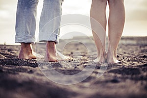 Closeup barefoot two couple of caucasian feet portrait on the beach. viewed from behind, love and intimate concept for young