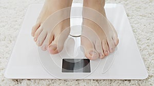 Closeup of barefoot woman using digital scales and checking her weight. Concept of dieting, loosing weight and healthy