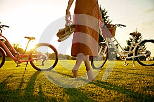 Closeup barefoot young female bicyclist on park grass lawn