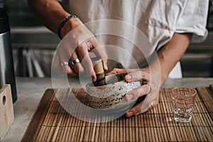 Closeup barista making japanese iced matcha latte, green tea with milk,traditional matcha tools, bamboo whisk