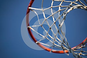 Closeup of basketball basket net of white rope view from underneath against a blue sky