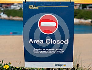 Closeup of a beach sign saying "Area closed" directed to the precautions of coronavirus.