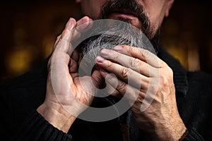 Closeup of a bearded man applying beard oil or serum, care treatment and men lifestyle