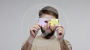 Closeup bearded man combining pieces of puzzle, jigsaw two parts of one, concept to find solution, complete elements