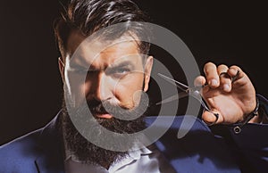 Closeup bearded man, portrait of man with long beard and moustache. Barber scissors for barber shop. Vintage barbershop