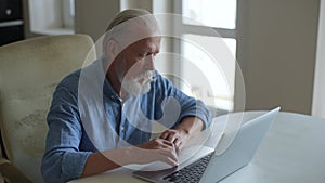 Closeup of bearded senior aged businessman in casual clothing suffering from wrist pain while working on laptop sitting