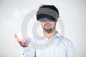 Closeup of bearded young man wearing virtual reality goggles in modern coworking studio. Smartphone using with VR headset