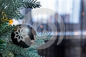 Closeup of beautiful Christmas matte silver black ball with snowflake hanging on Christmas tree on window background