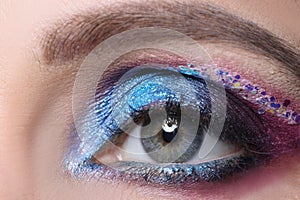 Closeup of beautiful female eye with bright shiny purple shadows
