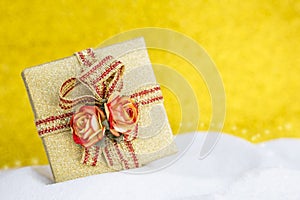 Closeup beautiful gold gift box with rose flower over blurred gold background