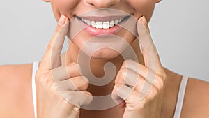 Closeup beautiful healthy smile and white teeth of a young attractive woman on grey background