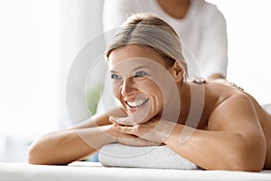 Closeup of beautiful middle aged woman enjoying back massage at spa salon